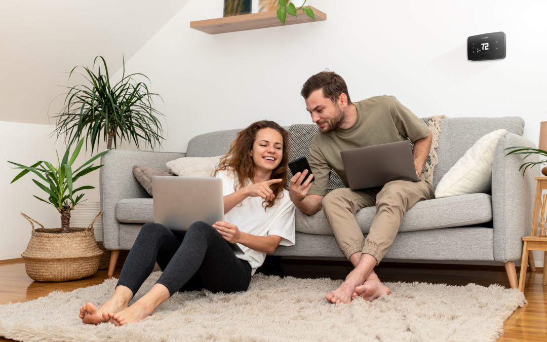 Man pointing on his phone to an energy management rebate with a Verdant VX4 smart thermostat installed in the room