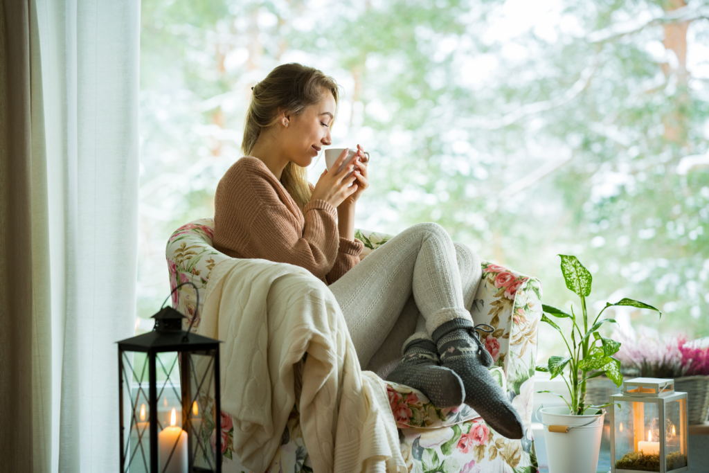 A woman sitting in a chair by the window with a cup of coffee during a demand response event