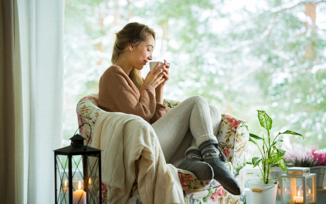 A woman sitting in a chair by the window with a cup of coffee during a demand response event